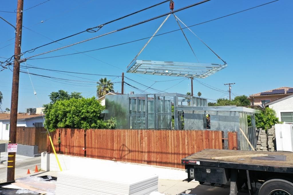 Crane setting a panelized light-gauge steel ADU frame on a Los Angeles County jobsite